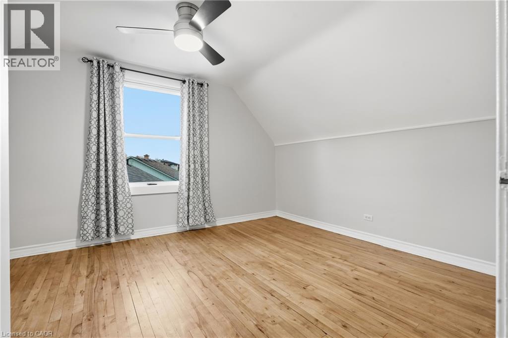 Hardwood flooring, painted walls, window with trim, sloped ceiling, and a ceiling fan - 160 Lorne Crescent, Kitchener, ON