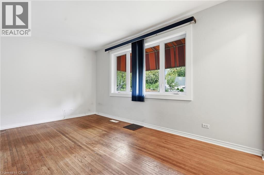 Light-filled room featuring wood-finish flooring, white walls, and a multi-pane window with white trim - 160 Lorne Crescent, Kitchener, ON