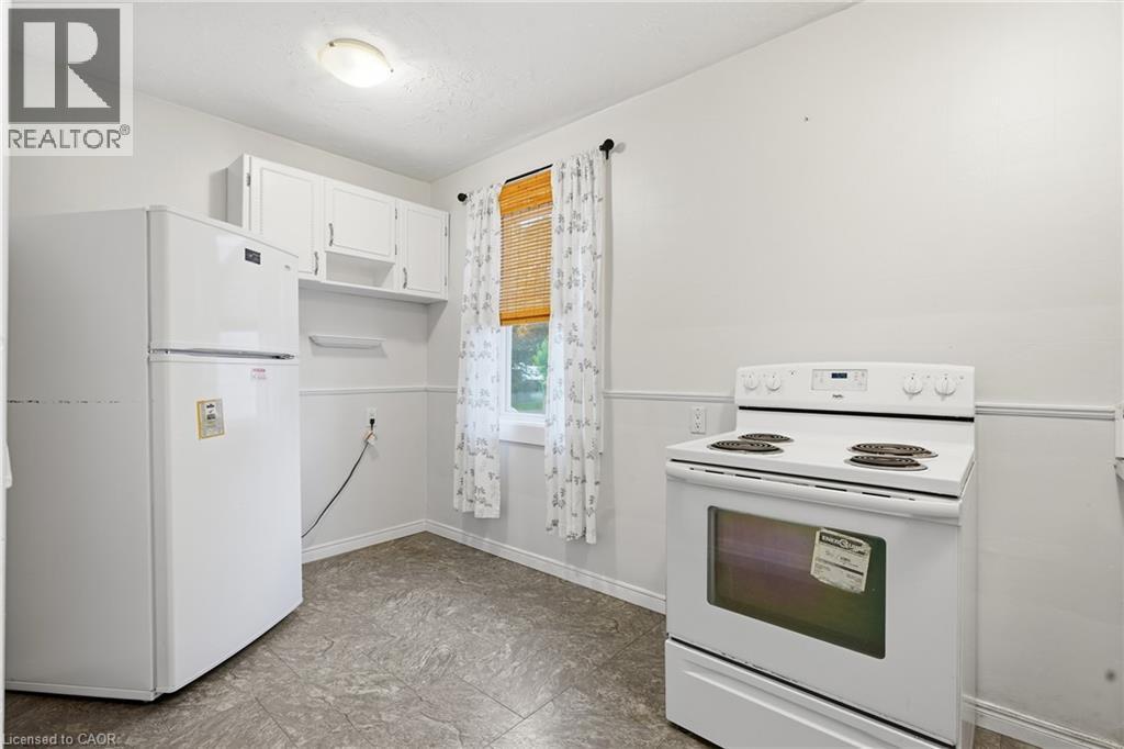 White kitchen appliances, upper cabinetry, a single window, overhead lighting, and resilient flooring - 160 Lorne Crescent, Kitchener, ON