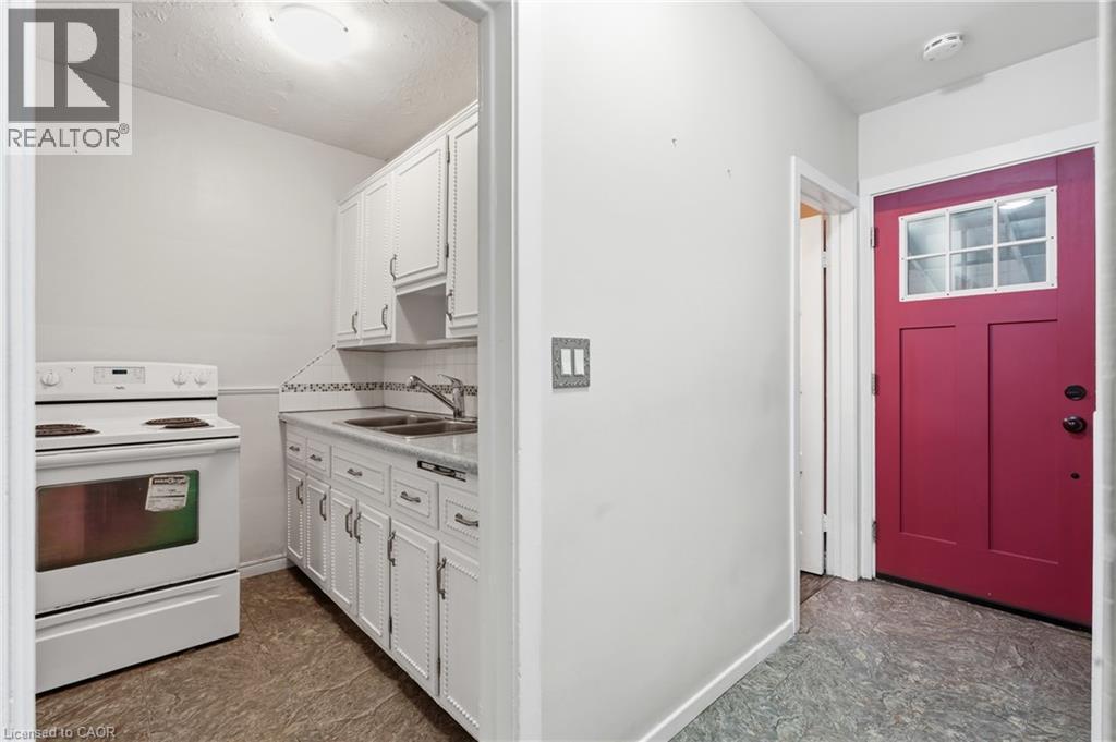 Compact kitchen with white cabinetry, white electric range, and a double basin sink - 160 Lorne Crescent, Kitchener, ON