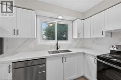 White shaker cabinetry with black hardware, white quartz countertops, full-height quartz backsplash, stainless steel dishwasher, and a double basin undermount sink with a matte black faucet - 