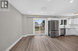 Wood-finish flooring, recessed lighting, white cabinetry, stainless steel appliances, and a sliding glass door to the exterior - 