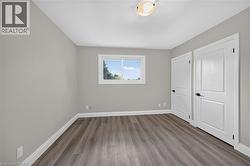 Wood-finish flooring, neutral wall tones, two paneled doors with dark hardware, and a flush mount ceiling fixture - 