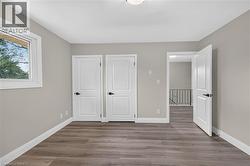 Light gray painted walls, wood-finish flooring, white trim, white panel doors with black hardware, and a single-pane window - 