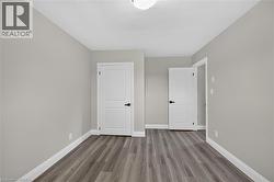 Neutral wall paint, wood-finish flooring, white trim, and white two-panel interior doors with dark hardware - 