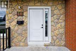 Stone and brick exterior featuring a white paneled front door with a sidelight, a bronze exterior light fixture, and a black mailbox - 