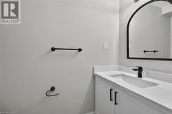 White vanity with integrated sink, black matte faucet, arched mirror, and white countertop - 