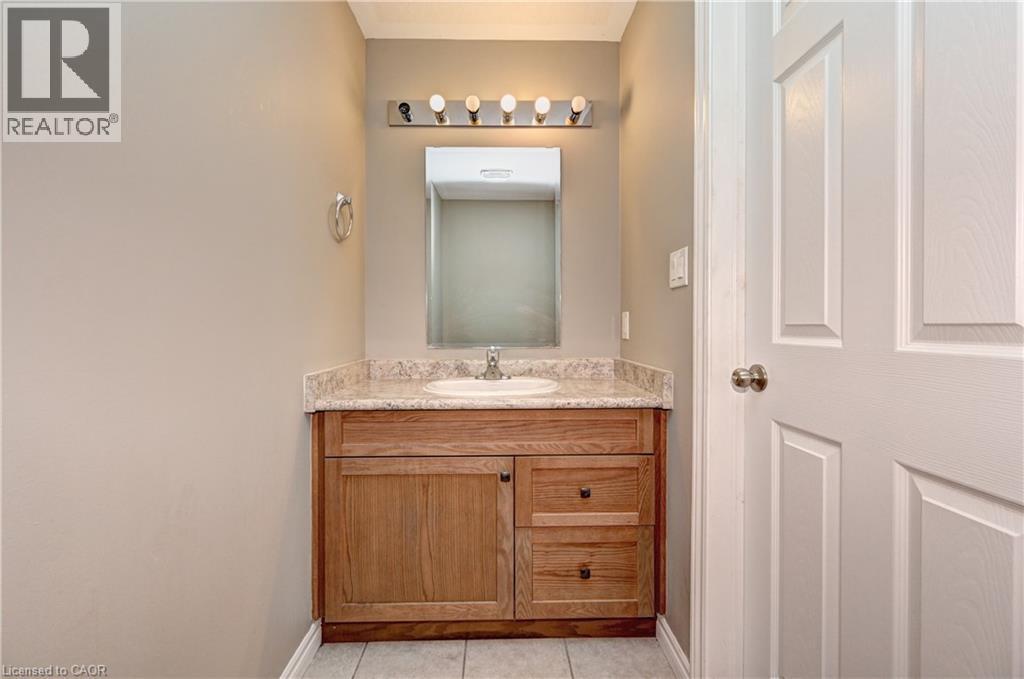 Vanity with wood-finish cabinetry, light-colored countertop, and integrated sink - 102 Wheat Lane, Kitchener, ON