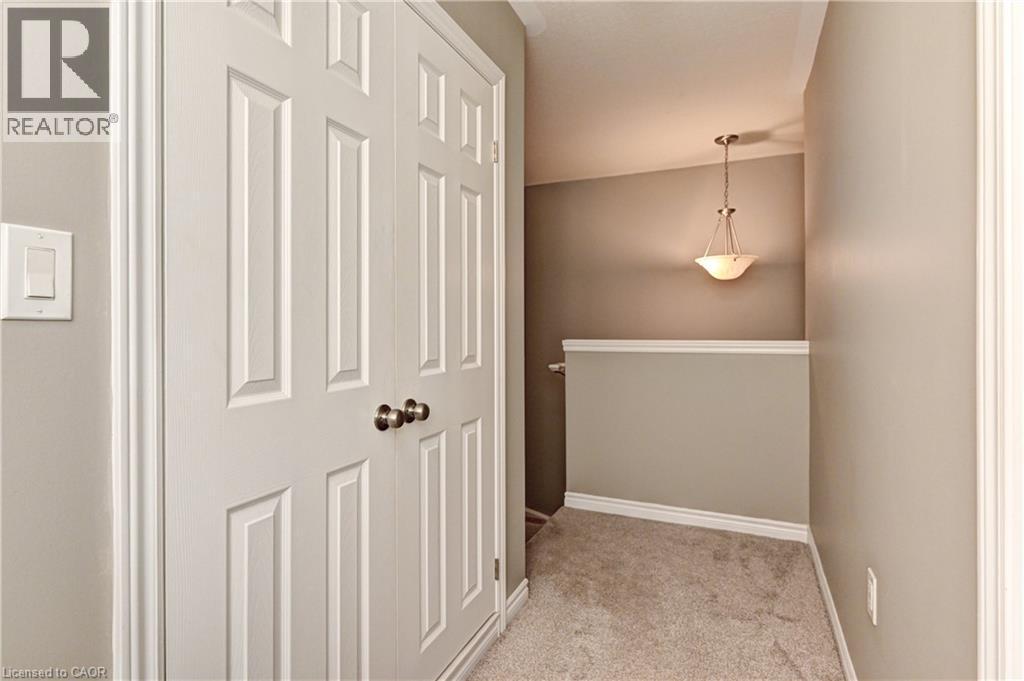 White paneled bifold doors, neutral tone walls, and recessed carpet flooring - 102 Wheat Lane, Kitchener, ON