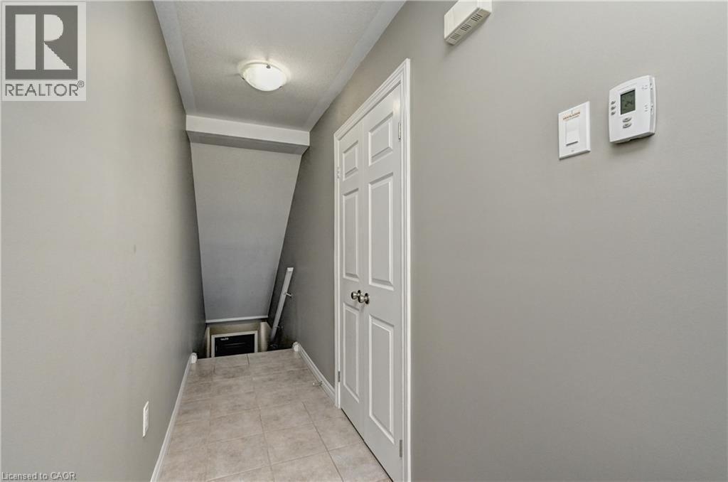 Recessed ceiling light fixture, neutral wall paint, white interior door with dark hardware, and tile flooring - 102 Wheat Lane, Kitchener, ON