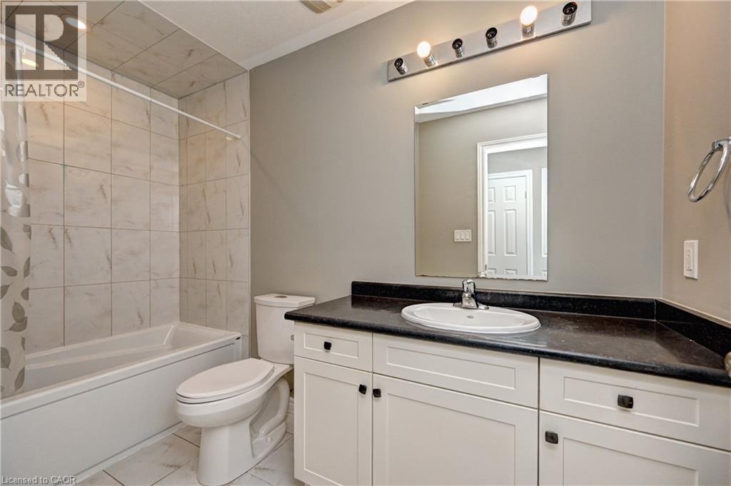 Bathroom with tiled flooring, white vanity, dark countertop, and integrated sink - 102 Wheat Lane, Kitchener, ON