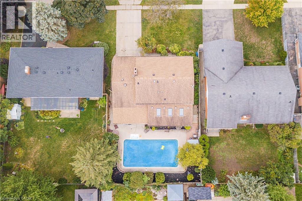 Aerial view showcasing an in-ground swimming pool with bright blue finish, entertaining area, and mature landscaping throughout the grounds. - 115 Southwood Drive, Cambridge, ON