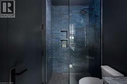 Shower enclosure featuring blue subway tile, matte black shower fixtures, and integrated shower niches - 