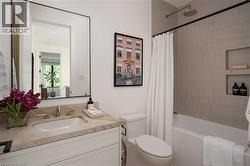 Bathroom featuring a white vanity with a stone countertop, an undermount sink, and a rectangular mirror with a black frame - 