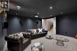 Dedicated media room featuring dark painted walls and ceiling, recessed lighting, wall-mounted speakers, and a ceiling-mounted projector - 
