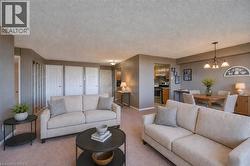 Living area featuring carpet flooring, suspended lighting, and a textured ceiling. Staged using AI - 
