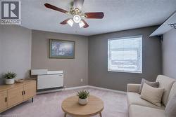 Sitting room with ceiling fan, a textured ceiling, and light colored carpet Staged using AI - 