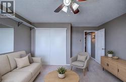 Sitting room with ceiling fan, a textured ceiling, and light colored carpet Staged using AI - 