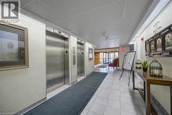 Corridor featuring elevator, a drop ceiling, a textured wall, and light tile patterned floors - 