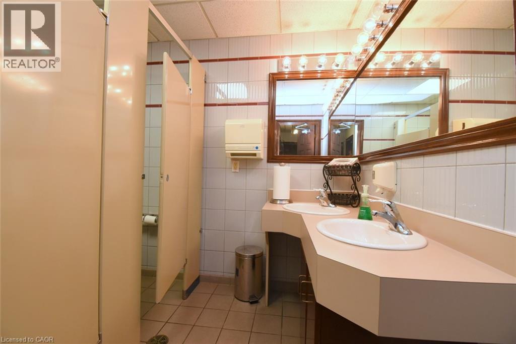 Modern bathroom featuring a curved vanity with an integrated sink, polished countertop surface, and contemporary wall-mounted faucet - 942-946 Barton Street E, Hamilton, ON