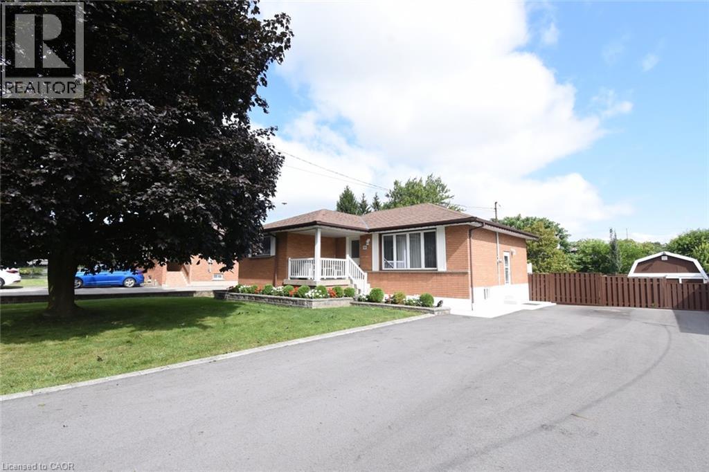Brick exterior with a covered front porch featuring white railings - 98 Kennedy Avenue, Hamilton, ON