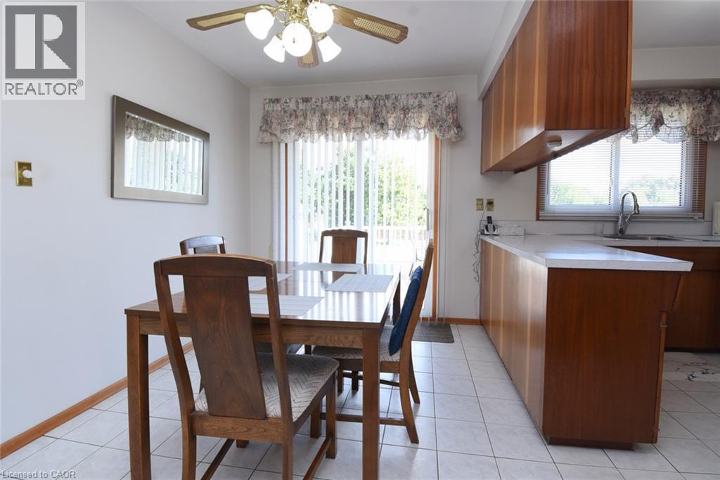 Kitchen with wood-finish cabinetry, white countertops, stainless steel sink, and white tile flooring - 98 Kennedy Avenue, Hamilton, ON