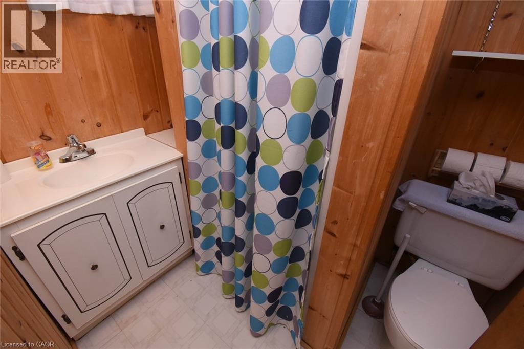 Bathroom featuring dual vanity with storage cabinetry, ceramic tile flooring, and a shower/tub combination with colorful patterned curtain liner - 98 Kennedy Avenue, Hamilton, ON