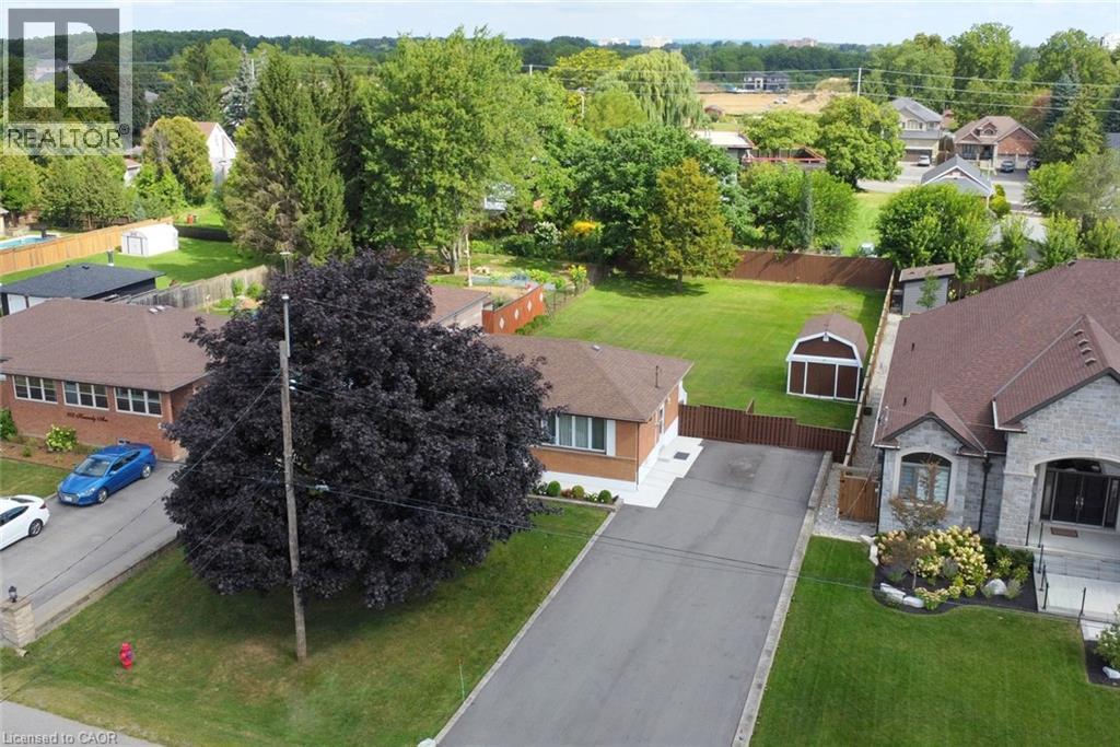 Spacious residential property featuring a brick ranch-style home with an attached garage, situated on a manicured lot with mature landscaping - 98 Kennedy Avenue, Hamilton, ON