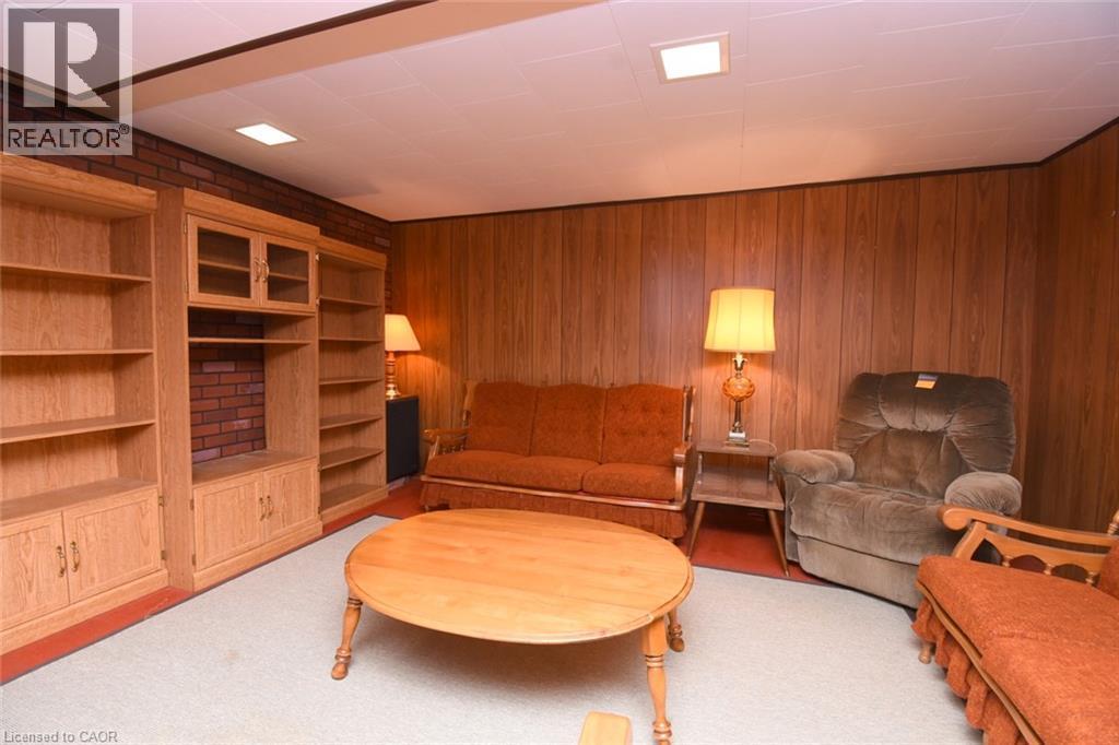 Built-in shelving with glass-front cabinetry, brick accent wall, wood-paneling, recessed lighting, and light-colored carpeting - 98 Kennedy Avenue, Hamilton, ON