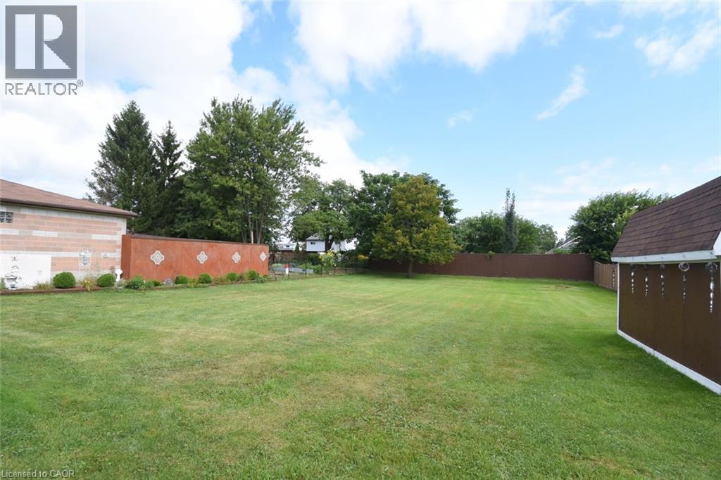 Expansive manicured lawn with mature landscaping, bordered by established trees and defined fencing - 98 Kennedy Avenue, Hamilton, ON