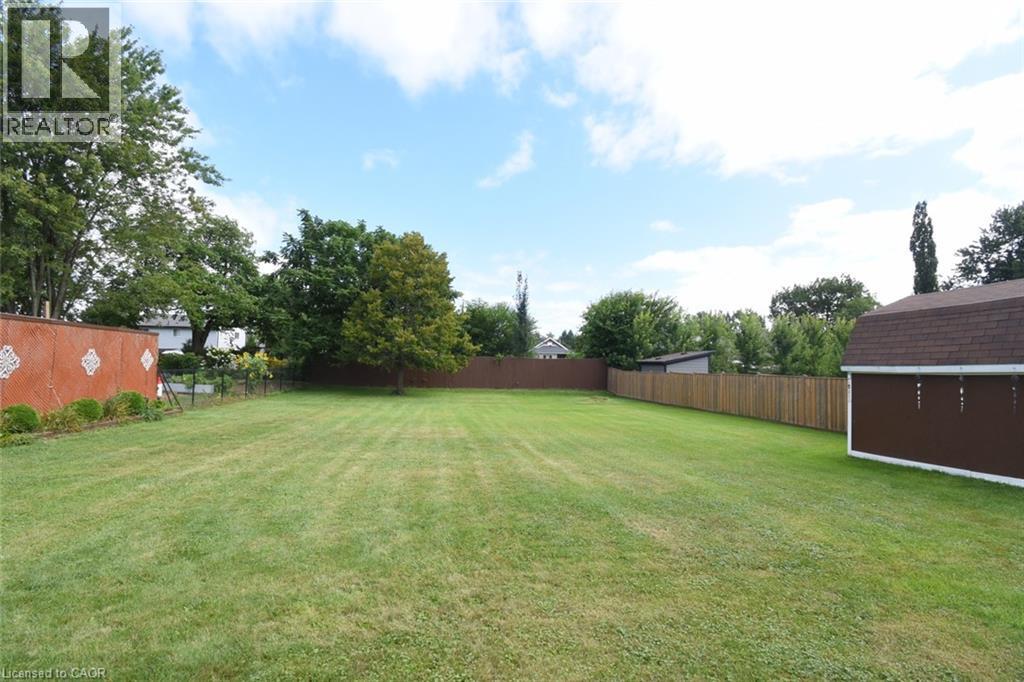 Expansive lawn with mature trees and a privacy fence - 98 Kennedy Avenue, Hamilton, ON