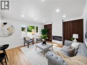 Spacious living area featuring light wood-finish flooring, recessed lighting, and a prominent fireplace with a white stone surround - 627 Upper Sherman Avenue, Hamilton, ON 