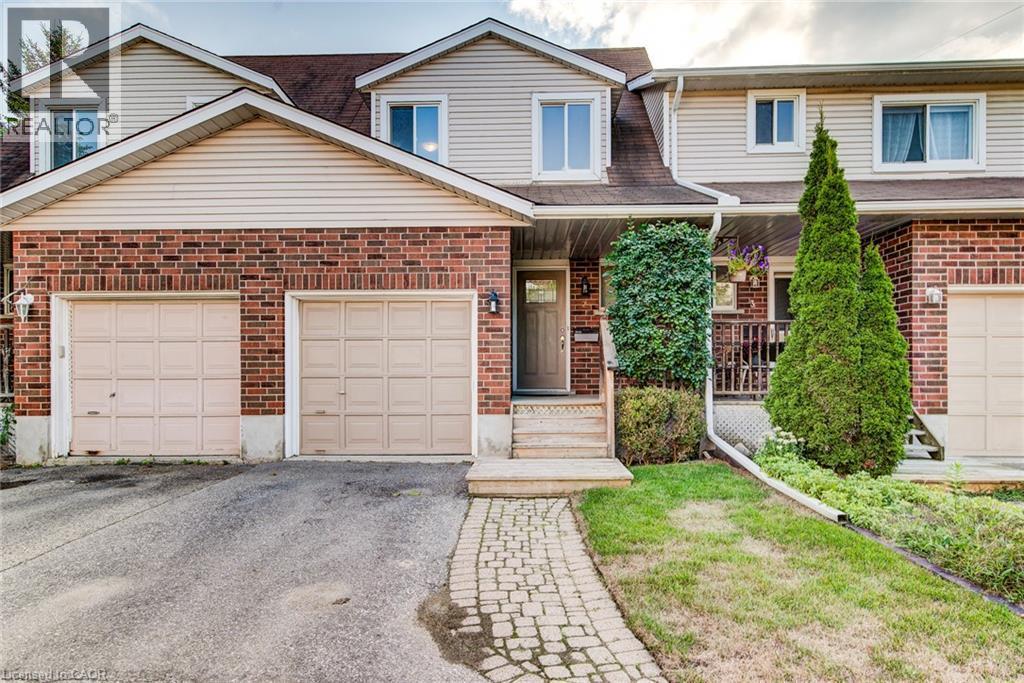 Brick and siding exterior with a pitched roofline, featuring two attached garage doors, a stone walkway, and established landscaping - 360 Cornridge Place Unit# 2, Waterloo, ON