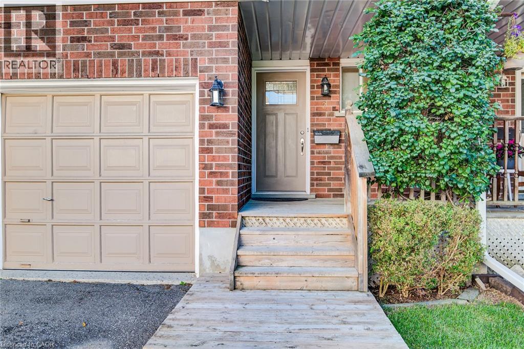 Brick exterior with panel garage door, covered entrance, and mature landscaping - 360 Cornridge Place Unit# 2, Waterloo, ON