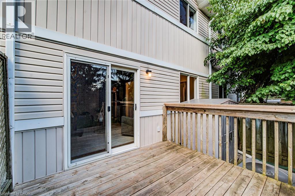 Wood deck with railing, featuring sliding glass door access, exterior wall sconce, and horizontal siding - 360 Cornridge Place Unit# 2, Waterloo, ON