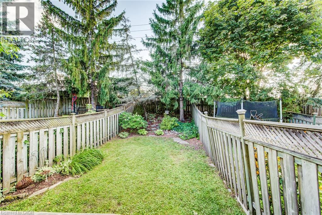 Expansive green lawn surrounded by wood fencing and mature trees - 360 Cornridge Place Unit# 2, Waterloo, ON