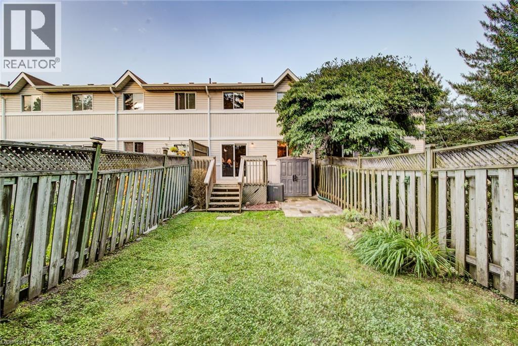 Rear yard featuring a grass lawn, privacy fencing, and mature trees - 360 Cornridge Place Unit# 2, Waterloo, ON