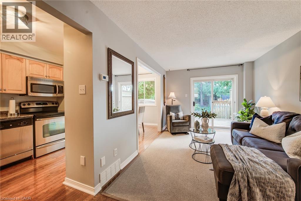 Living area with direct access to an outdoor deck, featuring light-colored walls and carpeted flooring - 360 Cornridge Place Unit# 2, Waterloo, ON