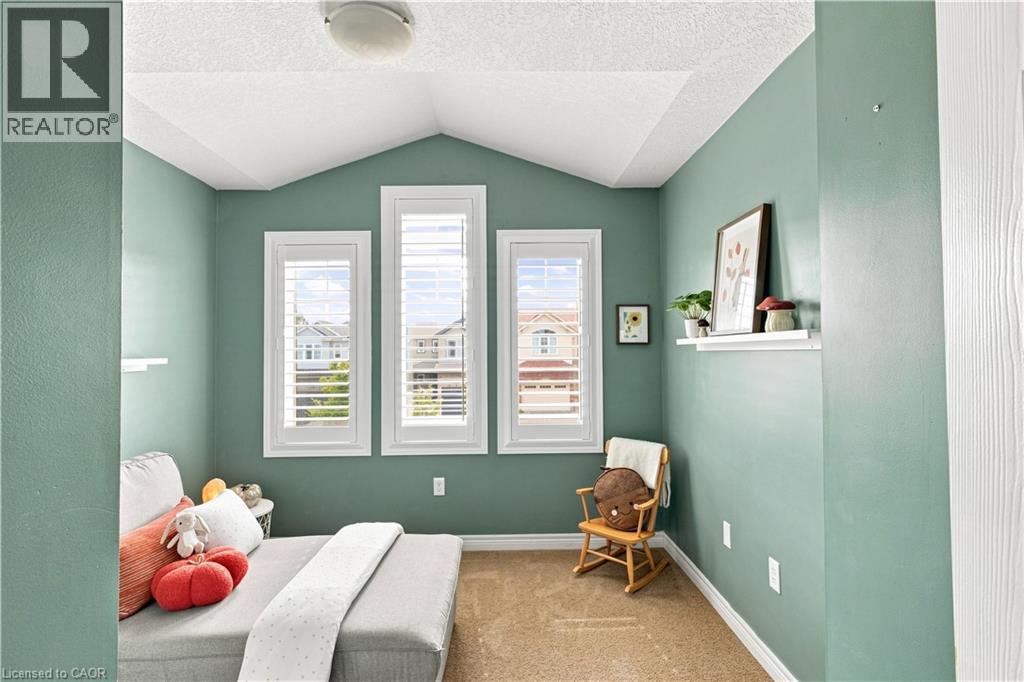 Serene bedroom retreat showcasing soft sage-green walls, white vaulted ceiling with recessed lighting, and triple casement windows with plantation shutters framing natural light - 187 Eden Oak Trail, Kitchener, ON