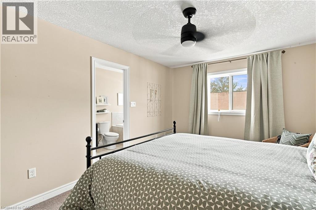 Room with a ceiling fan with integrated lighting, a window, and an open doorway leading to a bathroom with a toilet and built-in shelving - 187 Eden Oak Trail, Kitchener, ON