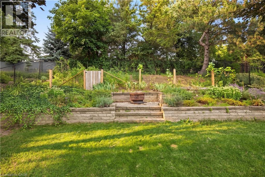 Expansive lawn area with a multi-tiered stone retaining wall and integrated steps - 62 Corfield Drive, Kitchener, ON
