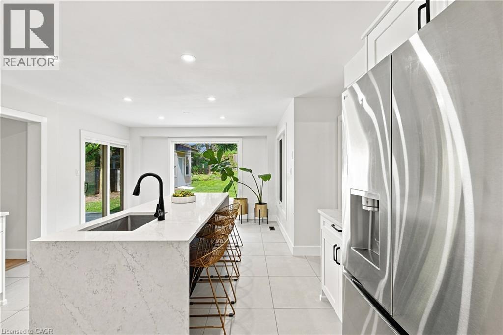 Kitchen island with a waterfall-edge countertop, undermount sink, and matte black faucet - 62 Corfield Drive, Kitchener, ON