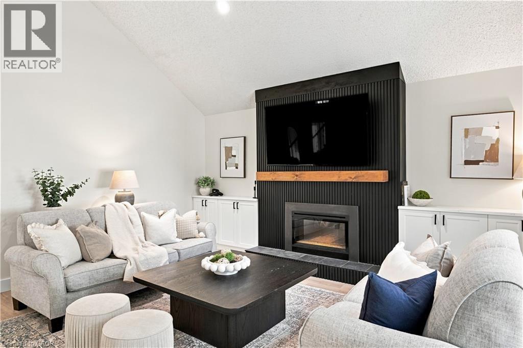 Vaulted ceiling, built-in fireplace, custom built-ins, wood mantel, and wood-finish flooring - 62 Corfield Drive, Kitchener, ON