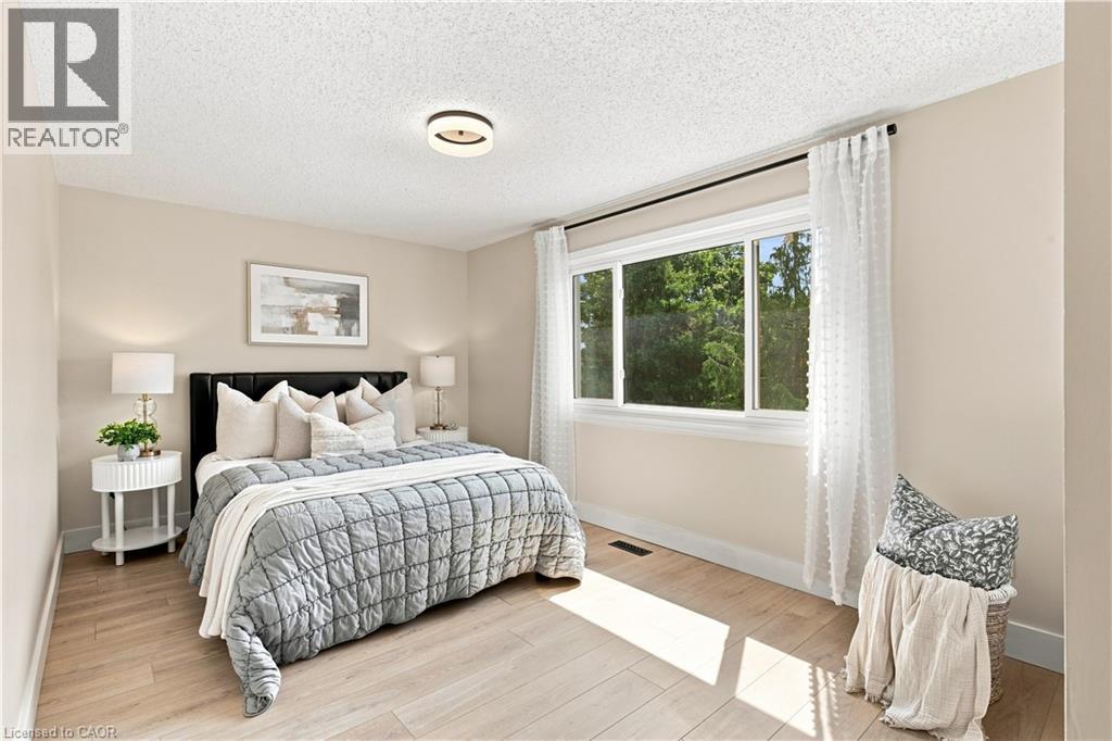 Light wood-finish flooring, a contemporary ceiling light fixture, and a large window with white trim - 62 Corfield Drive, Kitchener, ON