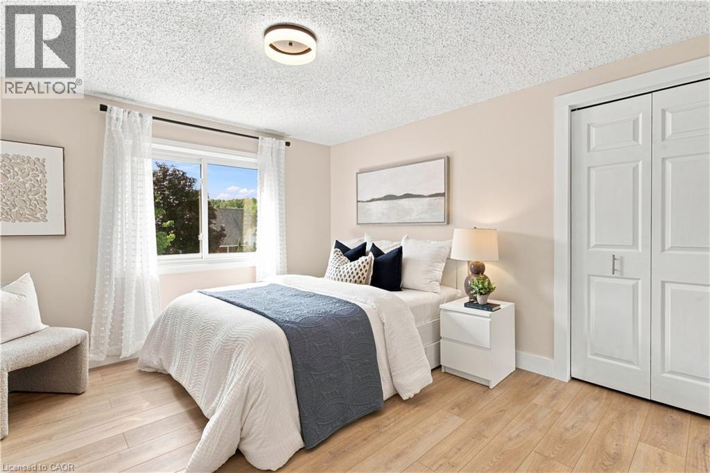 Wood-finish flooring, white bi-fold closet doors, contemporary flush-mount ceiling light, and a dual-pane window - 62 Corfield Drive, Kitchener, ON