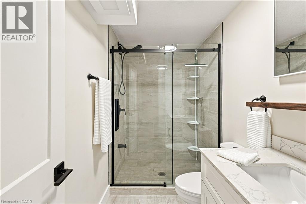 Glass-enclosed shower with subway tile surround, matte black fixtures, and a corner shelving unit - 62 Corfield Drive, Kitchener, ON