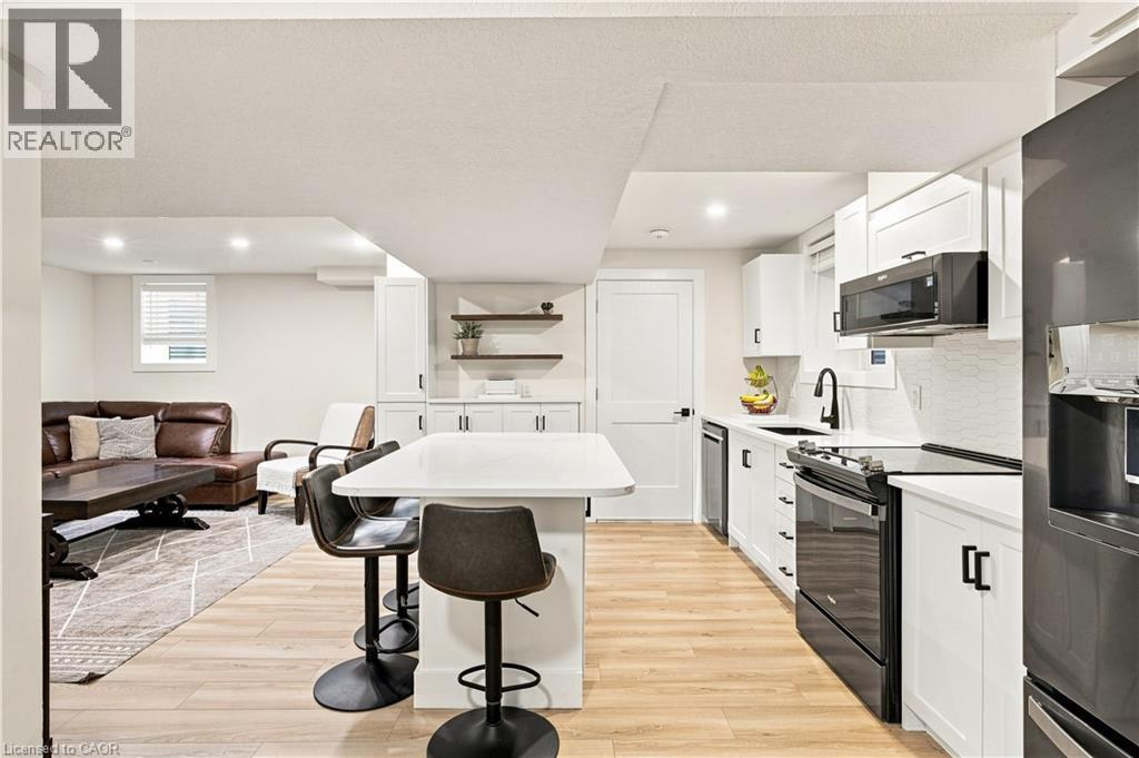 Modern kitchen featuring white cabinetry, black hardware, black appliances, light countertops, and wood-finish flooring - 62 Corfield Drive, Kitchener, ON
