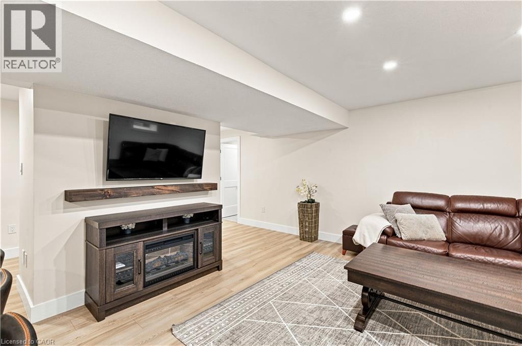 Recessed lighting, light wood-finish flooring, and a built-in media console with an electric fireplace - 62 Corfield Drive, Kitchener, ON
