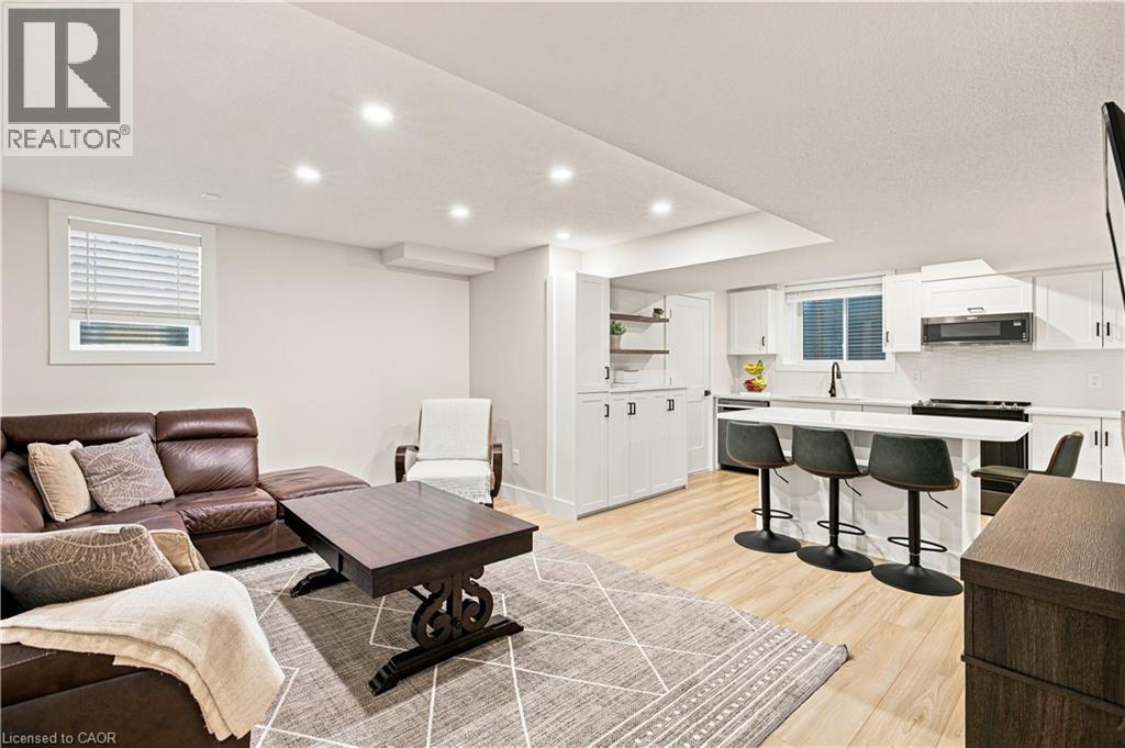 Recessed lighting illuminating a modern kitchen featuring white cabinetry, a built-in microwave, and a breakfast bar with seating - 62 Corfield Drive, Kitchener, ON