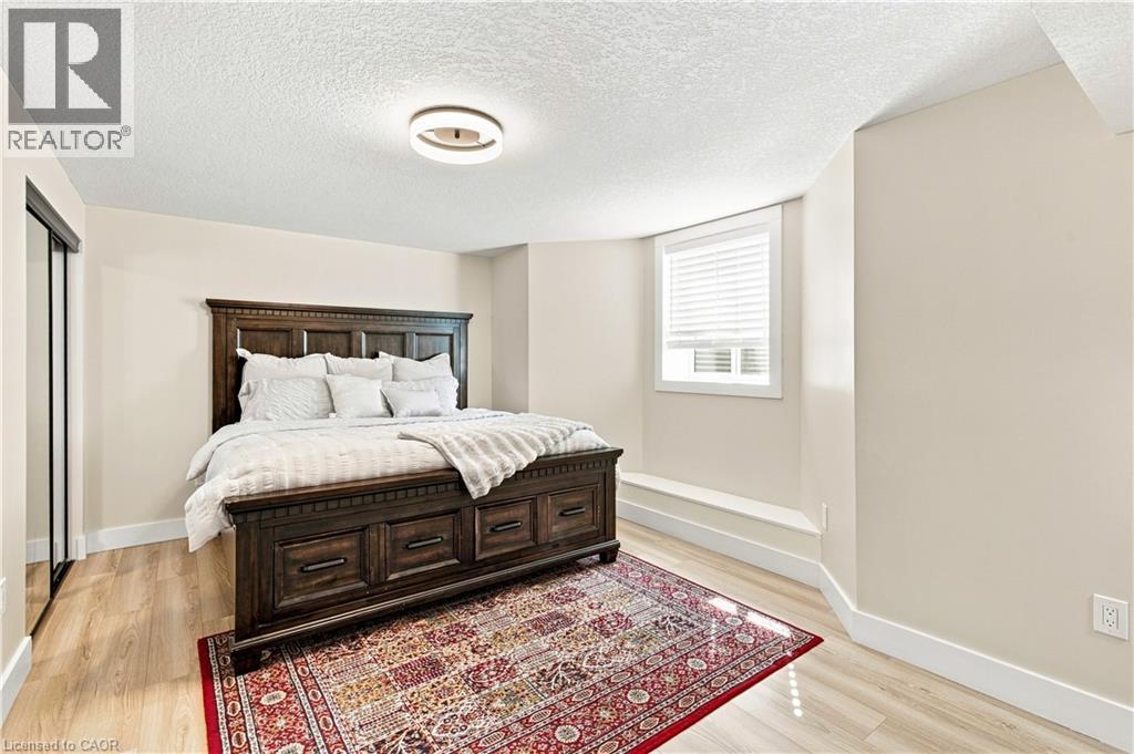 Wood-finish flooring, built-in window seat, window with blinds, recessed lighting, and mirrored closet doors - 62 Corfield Drive, Kitchener, ON